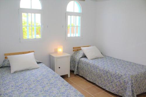 two beds in a room with two windows at Villa Chennai by Privilege Bay in La Oliva