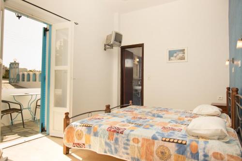 a bedroom with a bed and a balcony with a table at Villa Pelekanos in Karterados