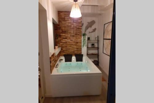 a bath tub in a room with a brick wall at LOVE ROOM OUT OF TIME *JACUZZI* in Itteville