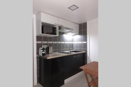 une petite cuisine avec une cuisinière et un micro-ondes dans l'établissement LOVE ROOM OUT OF TIME *JACUZZI*, à Itteville