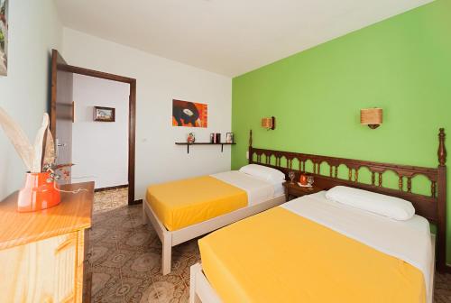 two beds in a room with green and yellow at Apartamentos Casa Blanca in Miami Platja