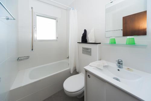 a white bathroom with a toilet and a sink at Apartamentos Casa Blanca in Miami Platja