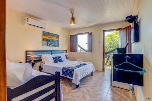 a hotel room with two beds and a window at Pousada Galeão Itacaré in Itacaré