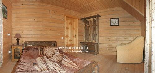 a bedroom with a bed in a log cabin at У Тарнавских in Mykulychyn