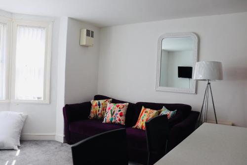 ein Wohnzimmer mit einem lila Sofa und einem Spiegel in der Unterkunft Garden Flat in the Heart of Southsea in Portsmouth