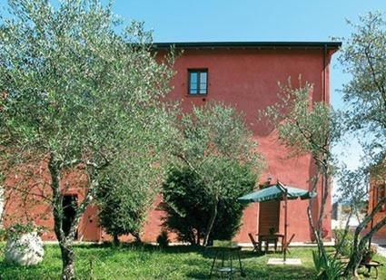 a red brick building with a picnic table and trees at Agriturismo La Villa in Bolano