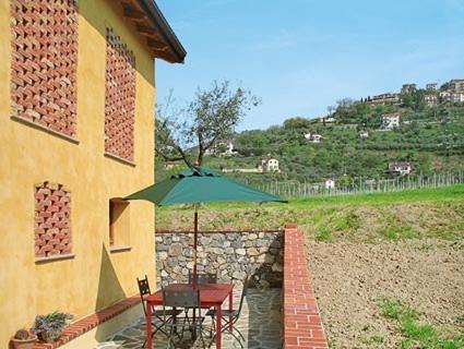 a table and chair with an umbrella next to a building at Agriturismo La Villa in Bolano