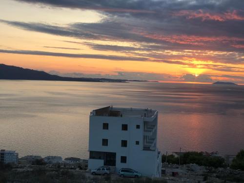 a building on the shore of a body of water at Hilltop Heaven Hotel in Sarandë