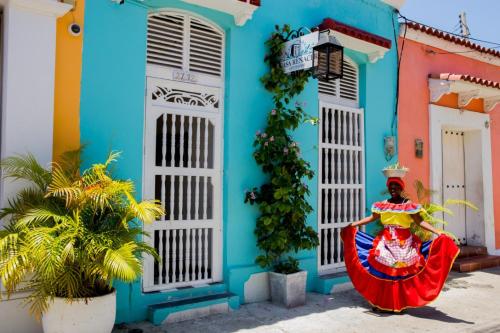Una donna con un vestito colorato in piedi davanti a un edificio blu di Casa Renacer a Cartagena de Indias