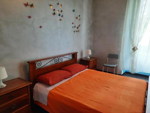 ジェノヴァにあるAppartamento Invreaのベッドルーム1室(オレンジのシーツと赤い枕が備わるベッド1台付)