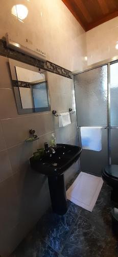 y baño con lavabo negro y ducha. en Pousada Pedacinho do Ceu suite Giulia 4, en Cunha