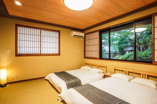 dwa łóżka w pokoju z dwoma oknami w obiekcie Shirakabanoyado - Izumi w mieście Izumisano