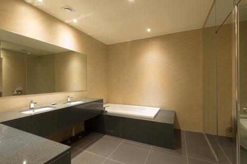 a bathroom with a tub and a sink and a mirror at The Empress Hotel in Daejeon