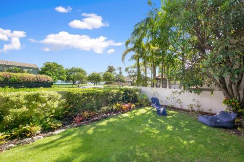 a yard with green grass and a fence and a tree at The Noosa Apartments in Noosa Heads