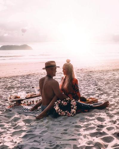 a man and a woman sitting on the beach at Igloo Beach Lodge in Manuel Antonio