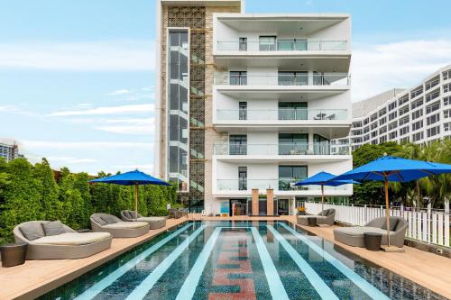 a swimming pool with chairs and umbrellas next to a building at Mera Mare Pattaya in Pattaya Central