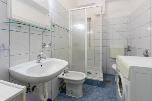 La salle de bains blanche est pourvue d'un lavabo et de toilettes. dans l'établissement Apartment Luksi, à Selce