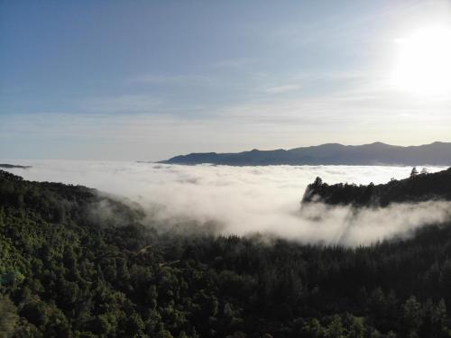 a view of a valley of clouds in the mountains at Golden Bay Glamping in Takaka