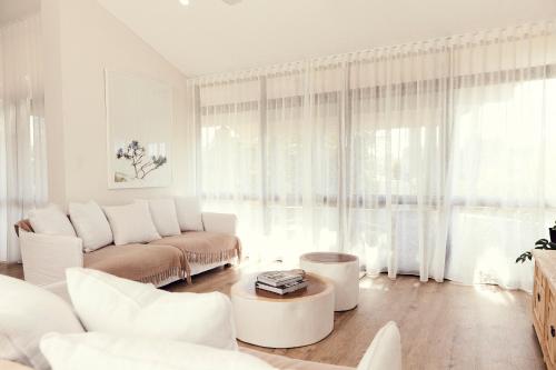 a white living room with a couch and a table at The Noosa Apartments in Noosa Heads