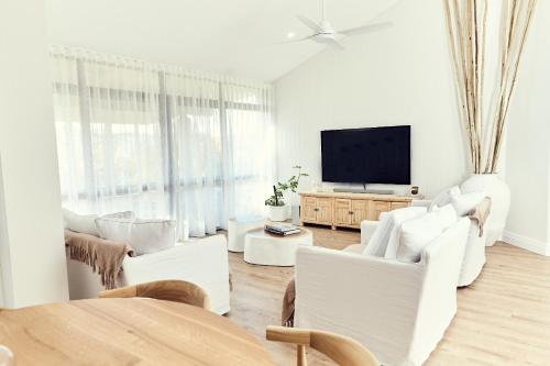 a living room with white furniture and a flat screen tv at The Noosa Apartments in Noosa Heads