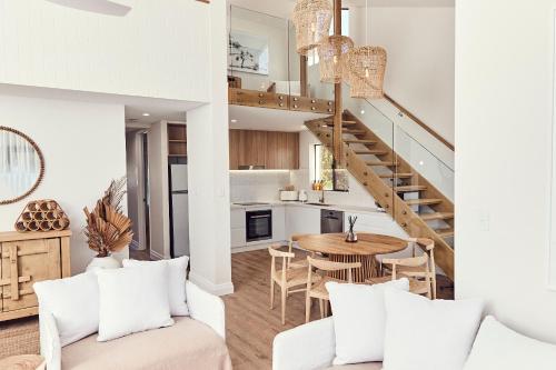 a living room with a staircase and a table and chairs at The Noosa Apartments in Noosa Heads