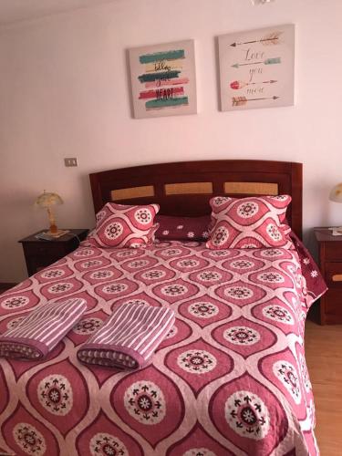 1 cama con almohadas y manta roja y blanca en Bienvenidos a mí casa, en Quilpué