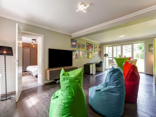 uma sala de estar com almofadas coloridas e uma televisão em Renovated farm with heated pool em Laakdal