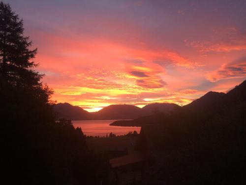a sunset over a body of water with mountains at Alpine Hideaway - 2 bedroom in Closeburn