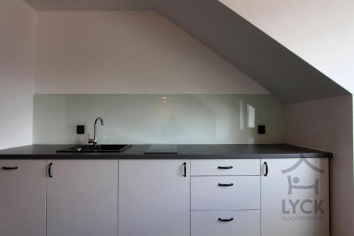 kuchnia z białymi szafkami i zlewem w obiekcie Lyck Apartamenty w mieście Ełk