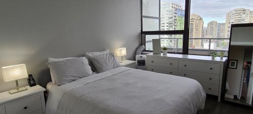 a bedroom with a white bed and a large window at Howe Street Apartment with Views in Vancouver