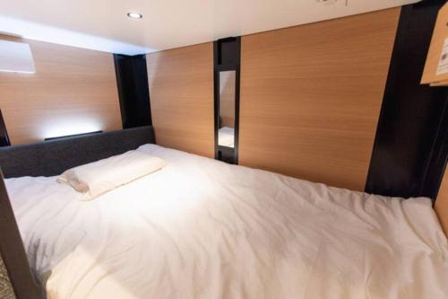 1 cama blanca grande en una habitación con paneles de madera en SAMURAI STAY 黄金町-Male Only, en Nishi-hiranumachō