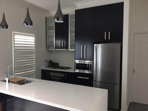 a kitchen with black cabinets and a stainless steel refrigerator at Chic 2 Bedroom Keilor in St Albans
