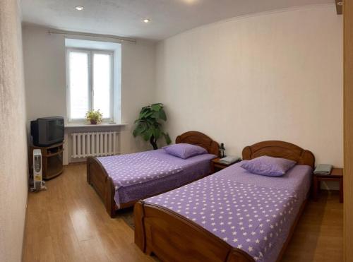 a bedroom with two beds and a tv and a window at Apartment style and comfort in Minsk