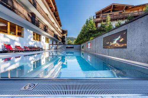 a swimming pool in a building with red chairs at Lifthotel in Kirchberg in Tirol