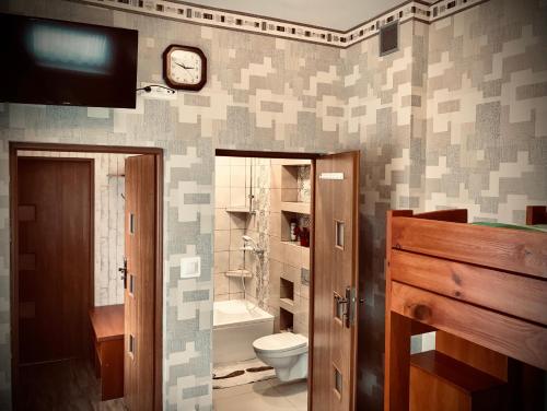 a bathroom with a toilet and a clock on the wall at Pokoje Goscinne Gallick in Gdynia
