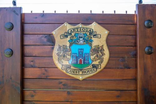 a crest of a guest house on a wooden fence at Antiqua Guest House in George
