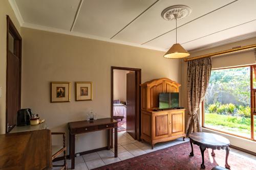 a living room with a table and a television at Antiqua Guest House in George