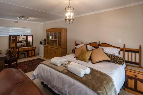 a bedroom with a large bed with towels on it at Antiqua Guest House in George