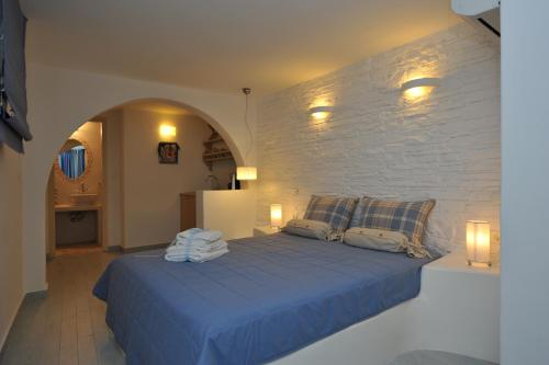 a bedroom with a blue bed with a stone wall at Villa Isabella in Naousa