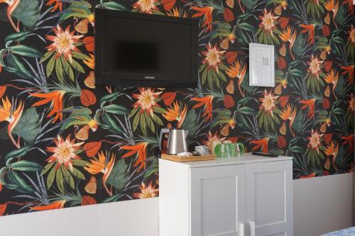 een televisie aan een muur met bloemenbehang bij Duinlust Dishoek in Dishoek