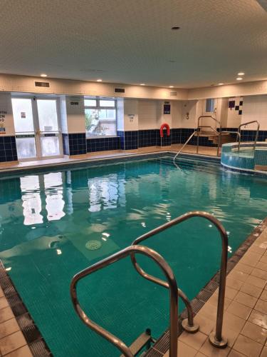 a large swimming pool with green water in a building at Durley Grange Hotel in Bournemouth