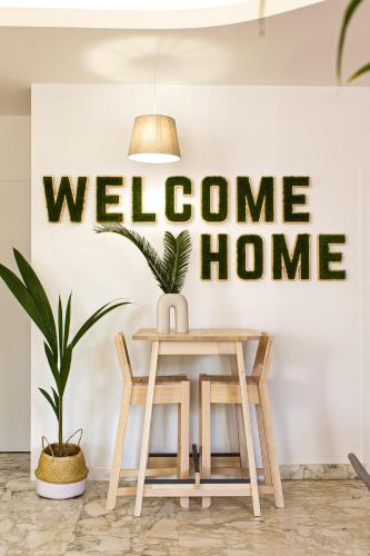 a table and chair in front of a welcome home sign at Hotel Blumen in San Benedetto del Tronto