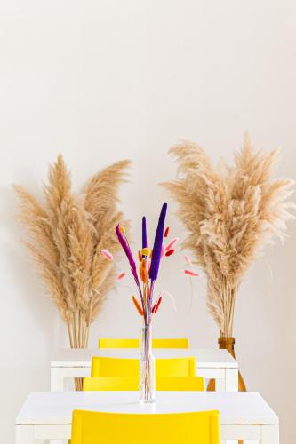 a table with yellow chairs and a vase with feathers at Hotel Blumen in San Benedetto del Tronto
