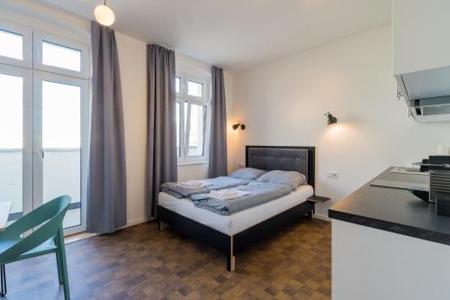 a bedroom with a bed and a desk and window at Nena Apartments Hermannplatz in Berlin