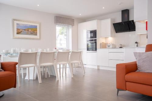 uma cozinha com armários brancos e uma mesa e cadeiras em Sea Breeze em Portstewart
