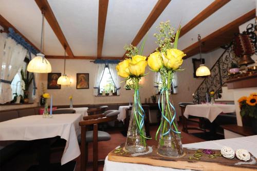 two vases with yellow roses on a table in a restaurant at Frühstückspension Haus Kreuzmayr in Gaschurn