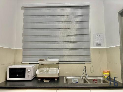 a kitchen with a sink and a microwave at Homesuite' Home at The Loft in Kota Kinabalu