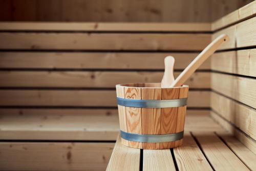 a wooden cup in a sauna with two wooden utensils at Hotel Neu-Schönstatt in Quarten
