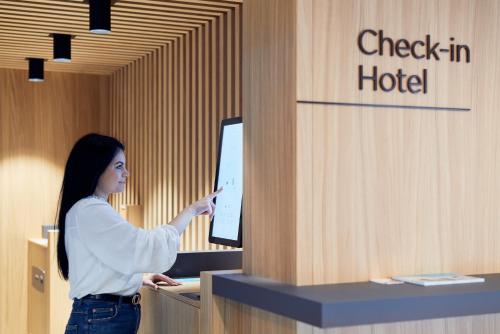 a woman standing at a counter pointing at a computer at Hotel Neu-Schönstatt in Quarten
