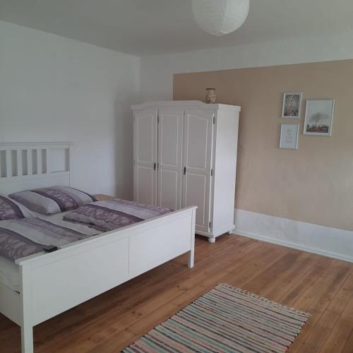 a bedroom with a white bed and a white cabinet at Familienhof Müritz in Klein Plasten